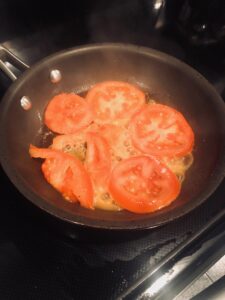 Tomato slices sauteing in a skillet