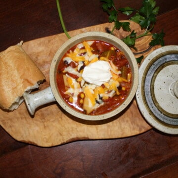 Veggie Chili in a crock with french bread and fresh parsley near by.