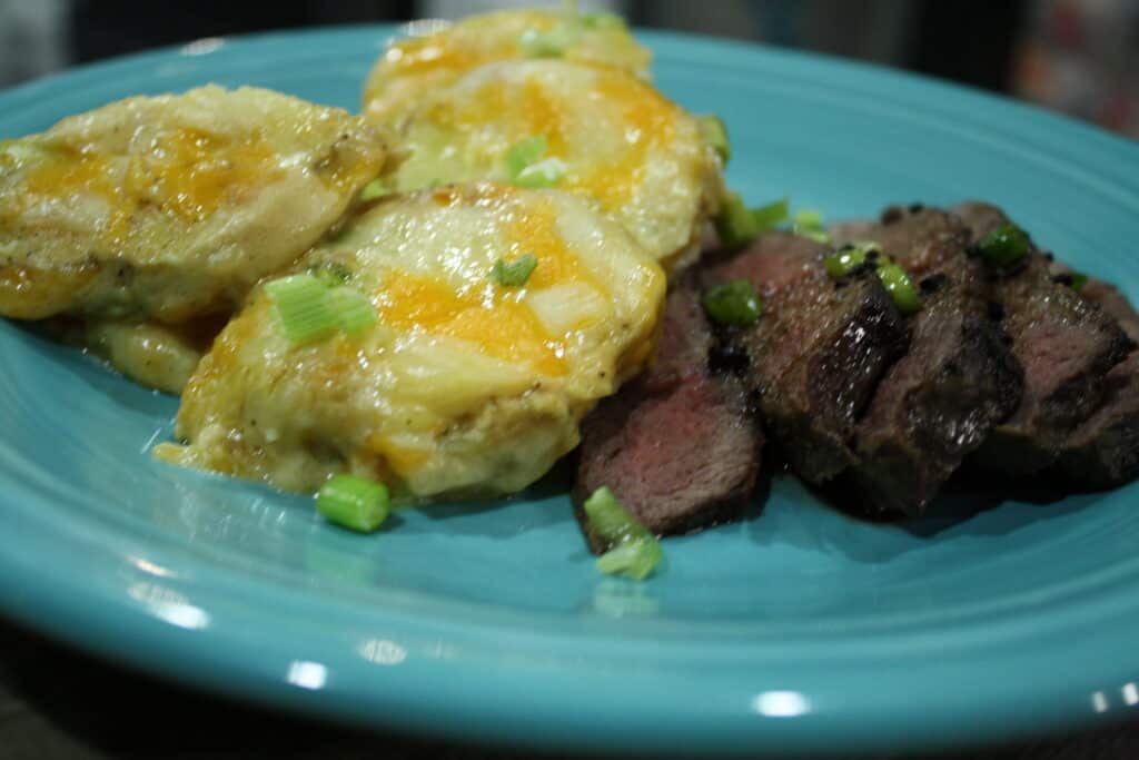 Quick and Easy Cheesy Scalloped Potatoes  and steak on a blue plate.