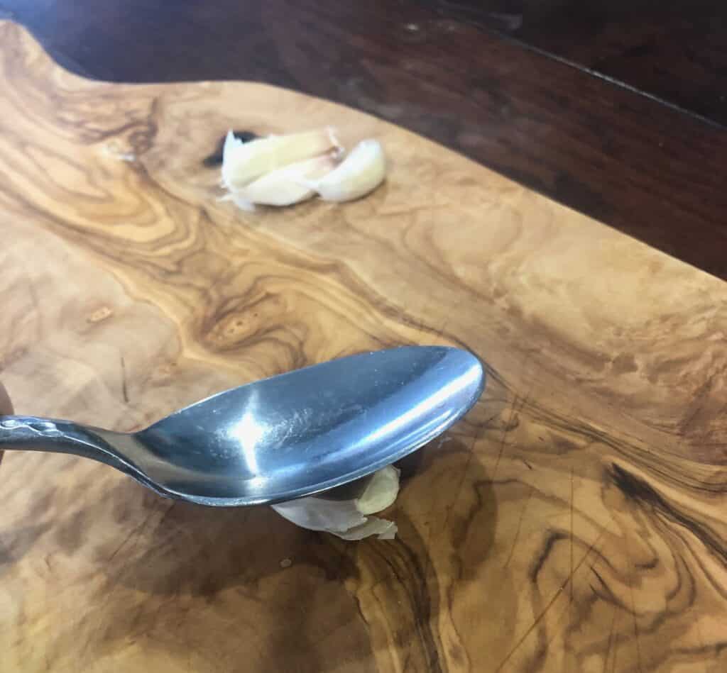 Pressing on garlic clove with a spoon.