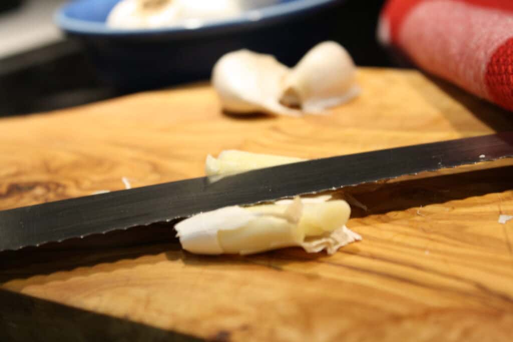 Pressing down firmly on garlic clove with a knife