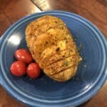 Baked Hasselback Potato on a Blue Plate with Cherry Tomatoes