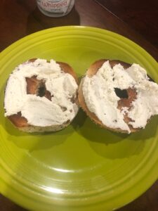 Everything bagel with cream cheese on a green plate