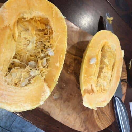 A spaghetti Squash sliced in two on a cutting board.