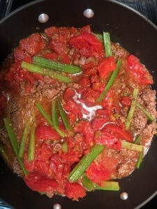 Bright green celery stewing in a sauce of ground beef and tomatoes.