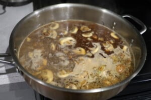adding chicken broth to the pan for chicken marsala