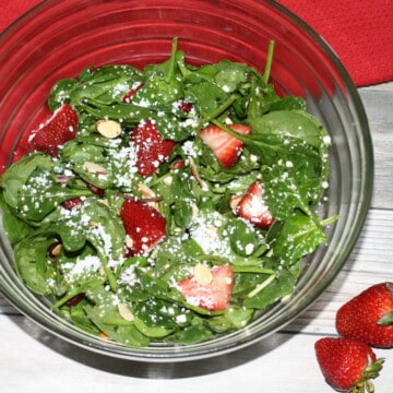 Strawberry Salad with Honey Vinaigrette in a salad bowl and two strawberries off to the side.