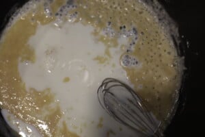 Adding milk to the roux and whisk.