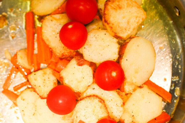 Skillet potatoes with carrots and tomatoes in a pan