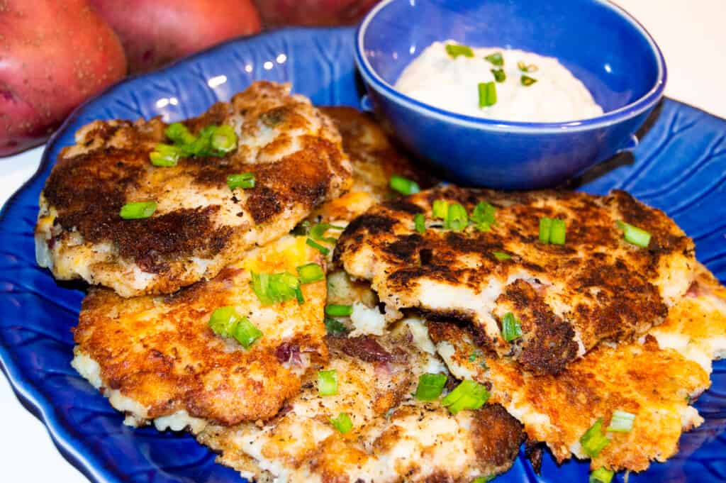 Delicious Potato Pancakes on a blue plate served with a side of horseradish dipping sauce.