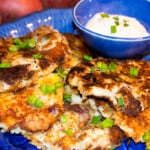 Delicious Potato Pancakes on a blue plate served with a side of horseradish dipping sauce.